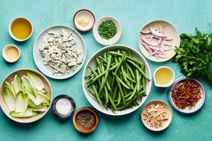 ingredients laid out for a vibrant green bean salad with honey dijon dressing, blue cheese, almonds and fried shallots