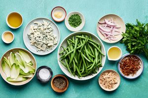 ingredients laid out for a vibrant green bean salad with honey dijon dressing, blue cheese, almonds and fried shallots