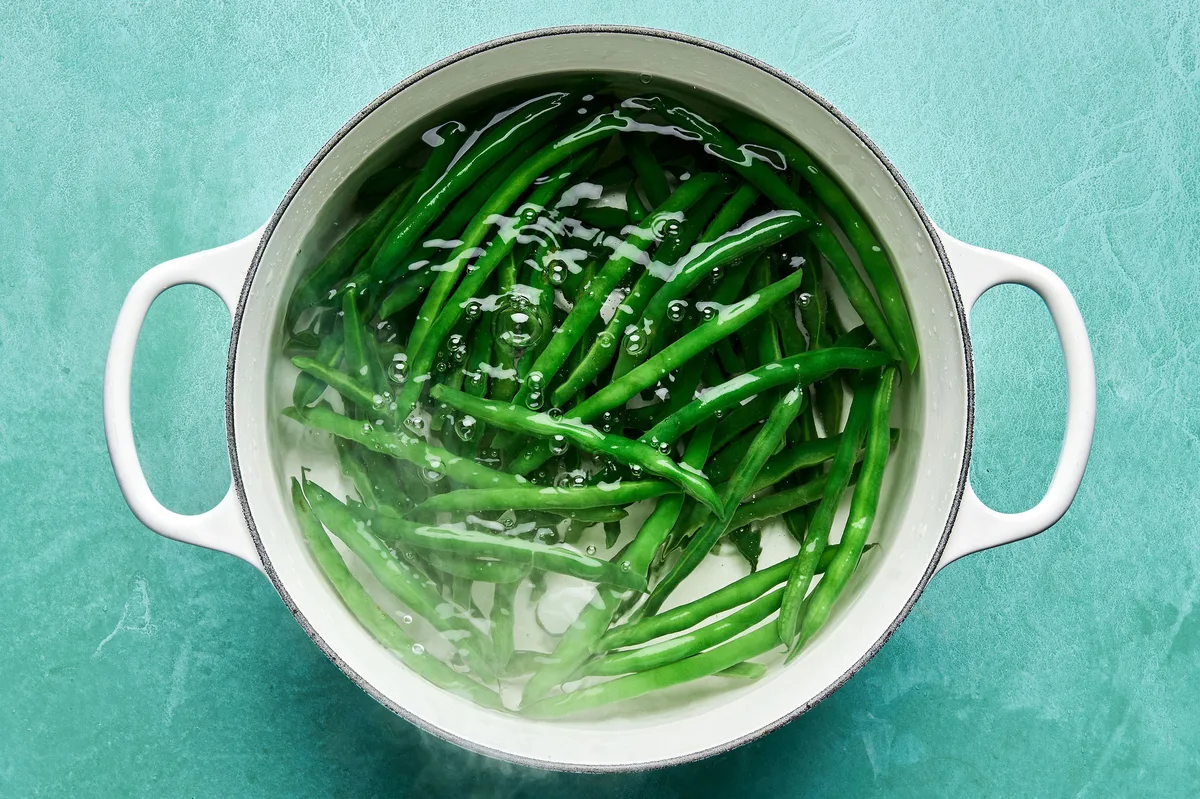Fresh green beans being blanched in a pot of boiling water to make them tender for a green bean salad