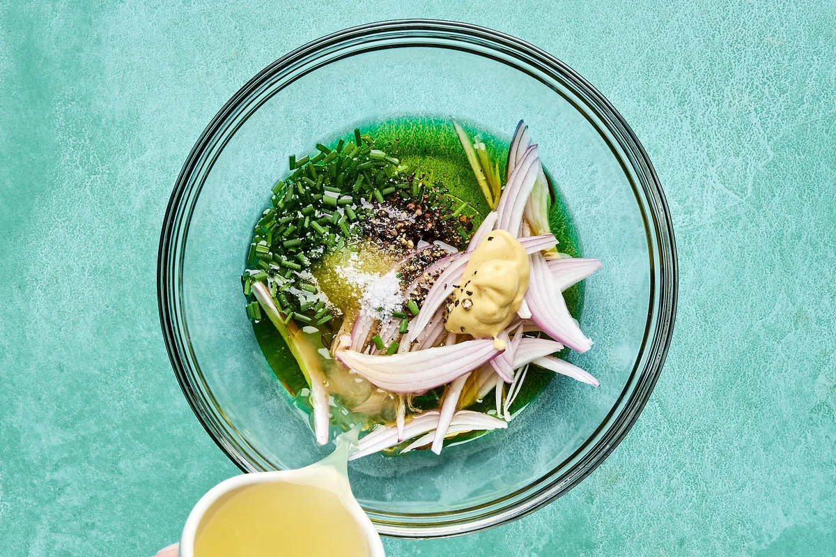 a honey dijon dressing being made with lemon juice, olive oil, mustard, honey, chives, shallot, salt, and pepper.
