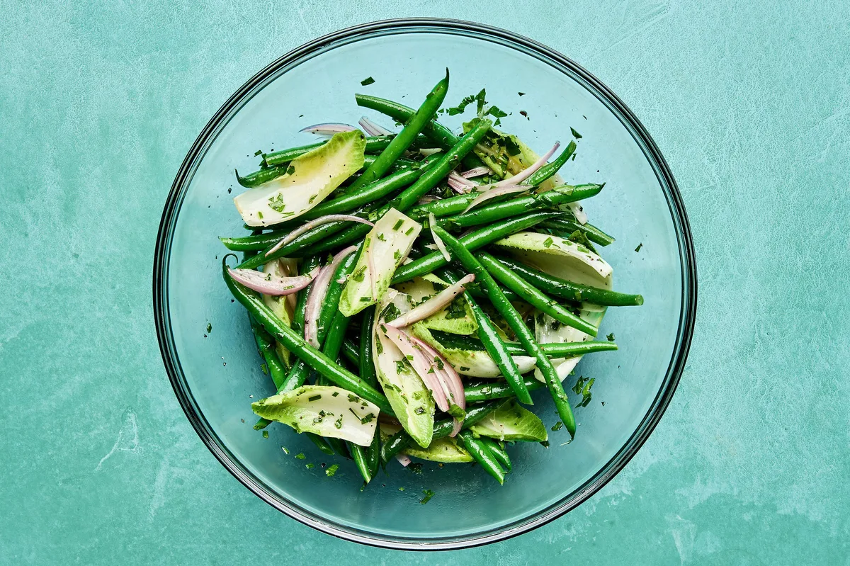 tender, blanched green beans being tossed with a homemade honey dijon dressing