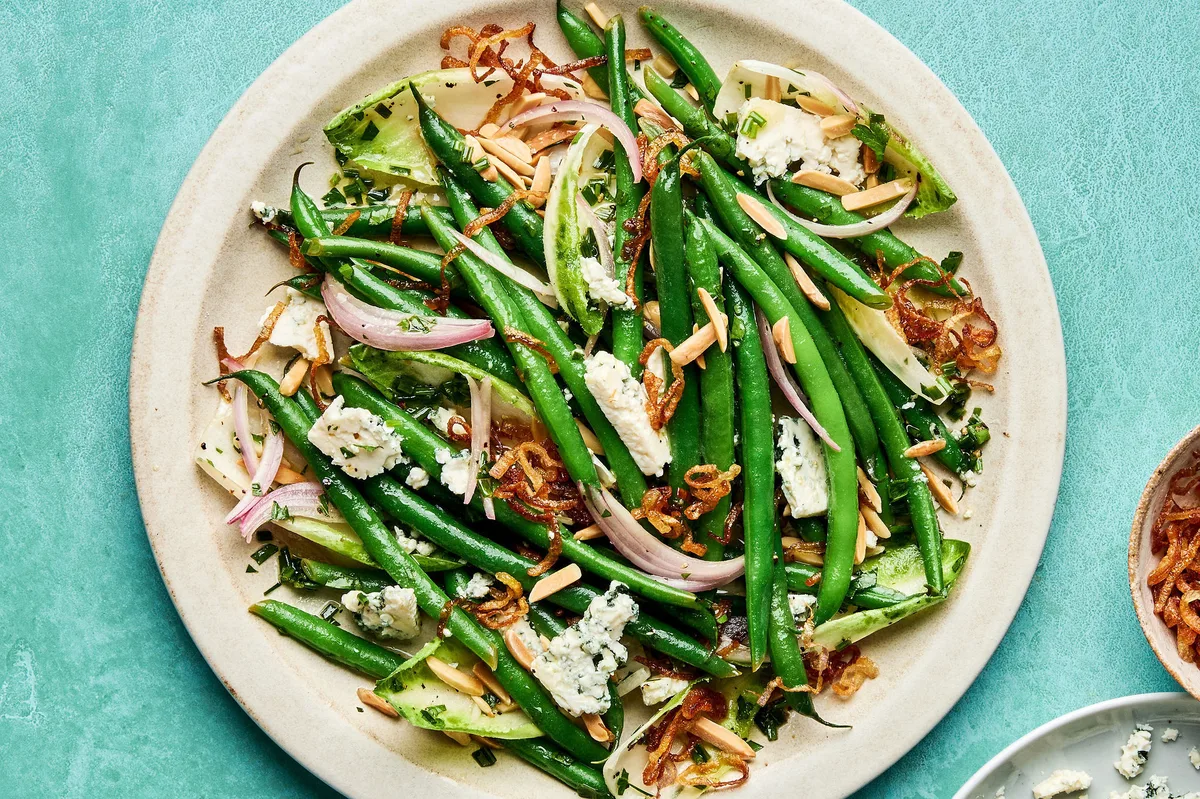 A vibrant green bean salad tossed in a honey Dijon dressing, topped with toasted almonds, blue cheese and fried shallots