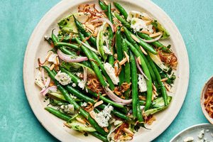 A vibrant green bean salad tossed in a honey Dijon dressing, topped with toasted almonds, blue cheese and fried shallots