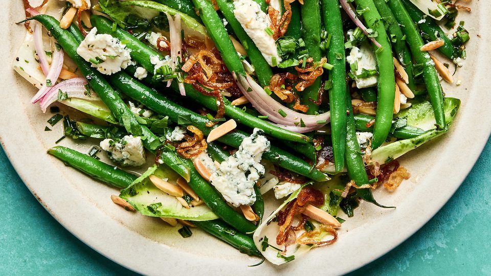 A vibrant green bean salad tossed in a honey Dijon dressing, topped with toasted almonds, blue cheese and fried shallots