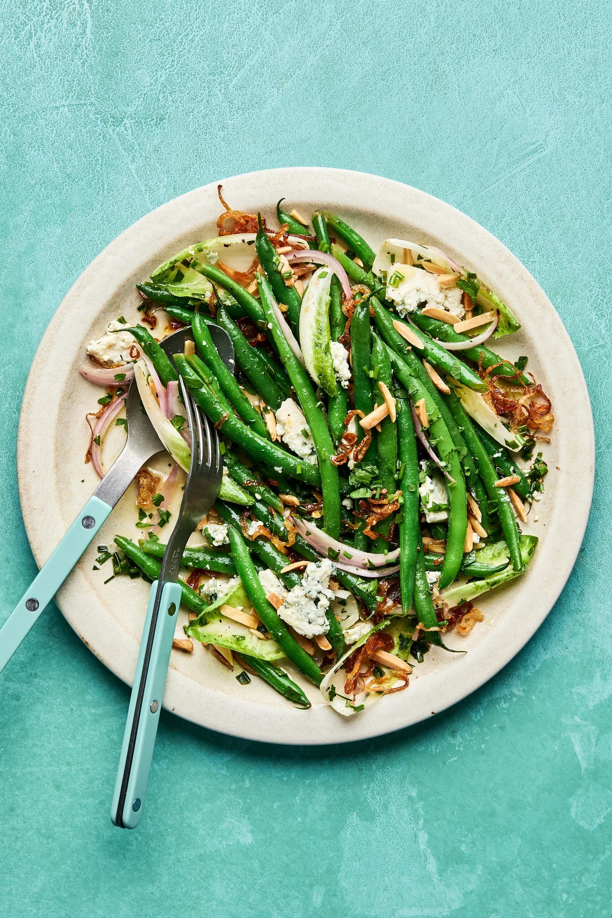 A vibrant green bean salad tossed in a honey Dijon dressing, topped with toasted almonds, blue cheese and fried shallots