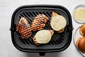 balsamic chicken being cooked on a grill with provolone cheese melting on top