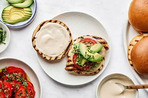 brioche buns being topped with juicy grilled chicken, provolone, marinated tomatoes, balsamic mayo & avocado