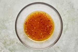 marinade for chicken in a bowl made with sugar water, fish sauce, olive oil, lime juice, grated garlic, chili sauce and salt.