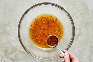 marinade for chicken in a bowl made with sugar water, fish sauce, olive oil, lime juice, grated garlic, chili sauce and salt.