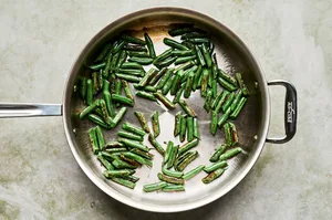 fresh green beans being cooked in olive oil in a skillet until blistered