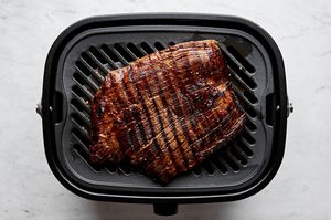 flank steak marinated in olive oil, apple cider vinegar and spices being cooked on a grill