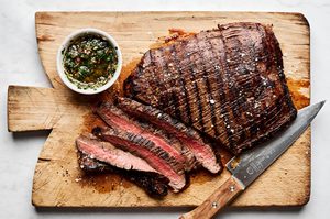 Juicy grilled flank steak sliced on a cutting board, marinated with apple cider vinegar, olive oil and spices