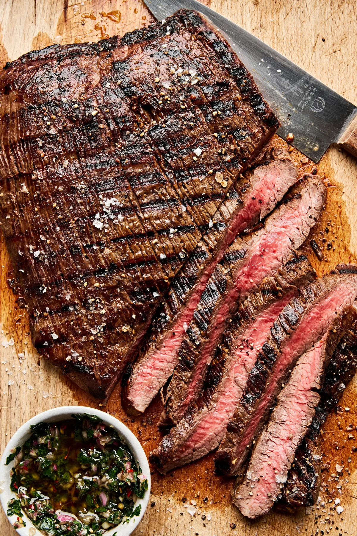 Juicy grilled flank steak sliced on a cutting board, marinated with apple cider vinegar,  olive oil and spices
