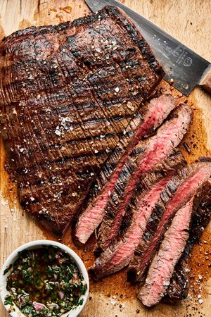 Juicy grilled flank steak sliced on a cutting board, marinated with apple cider vinegar, olive oil and spices