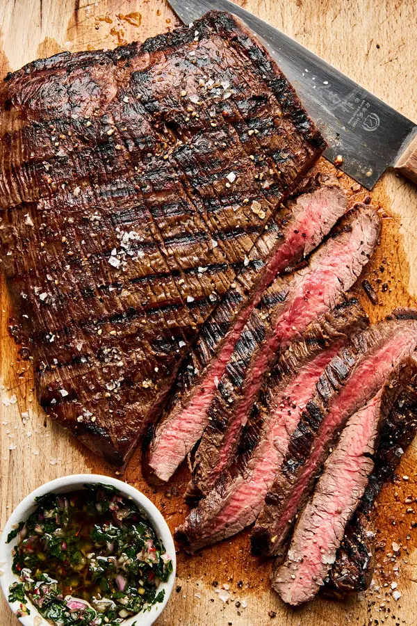 Juicy grilled flank steak sliced on a cutting board, marinated with apple cider vinegar, olive oil and spices