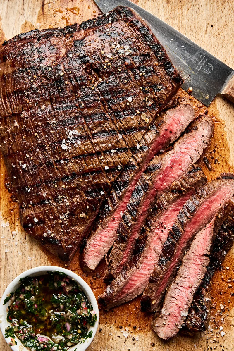Juicy grilled flank steak sliced on a cutting board, marinated with apple cider vinegar,  olive oil and spices