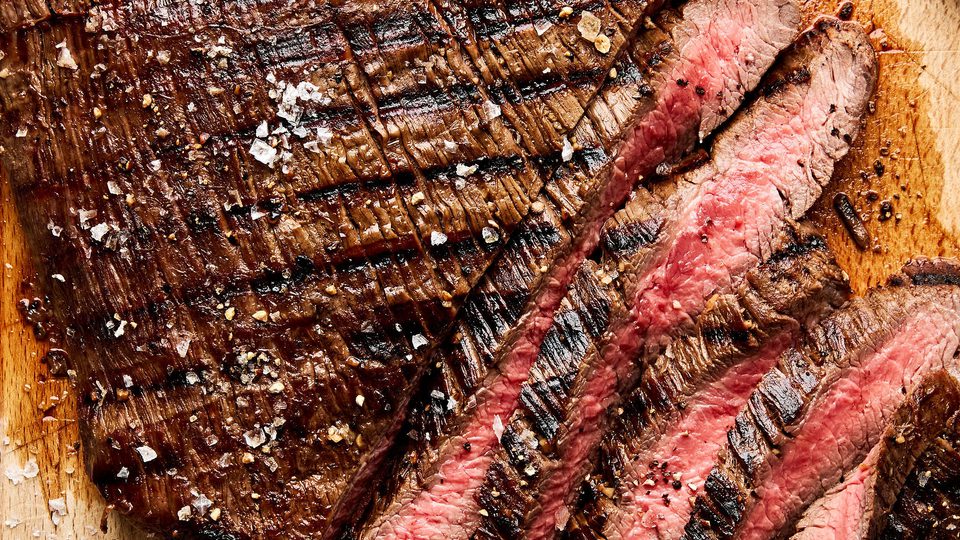 Juicy grilled flank steak sliced on a cutting board, marinated with apple cider vinegar,  olive oil and spices