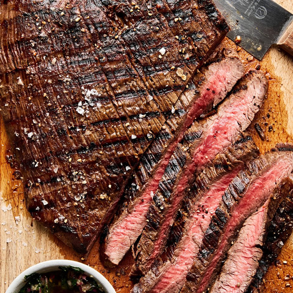 Juicy grilled flank steak sliced on a cutting board, marinated with apple cider vinegar,  olive oil and spices