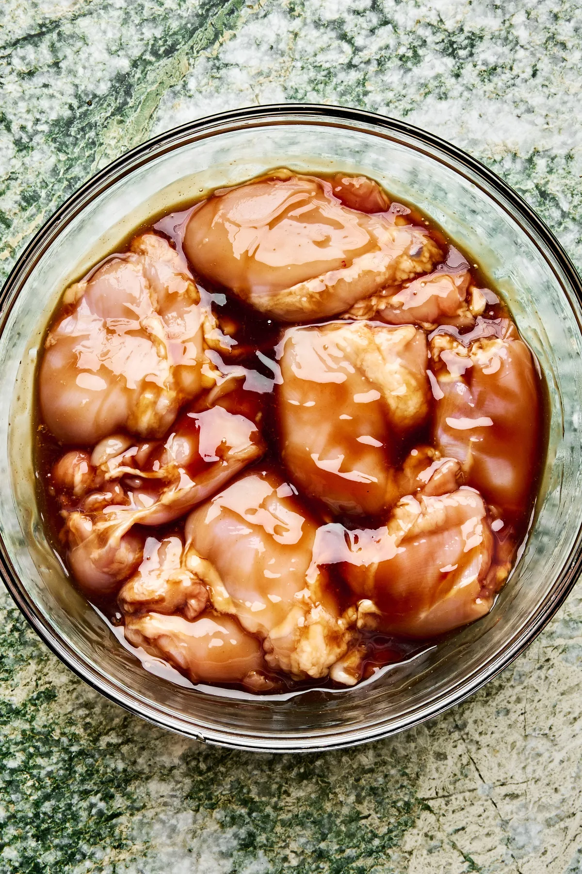 boneless, skinless chicken thighs marinating in homemade teriyaki sauce in a large bowl