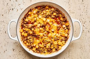 a hearty one pot dinner of ground beef and potatoes, topped with cheddar cheese in a skillet