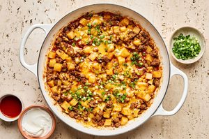 a simple one pot dinner of ground beef and potatoes, topped with cheddar served with green onion, sour cream & hot sauce