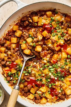 a simple one pot dinner of ground beef and potatoes, topped with cheddar served with green onion, sour cream & hot sauce