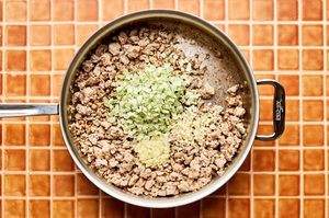 Garlic, cabbage and ginger being added to browned ground turkey in a pan to make a low-carb ground turkey stir fry