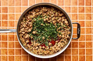 Fresh cilantro and basil being stirred into a pan of ground turkey stir-fry with homemade stir-fry sauce