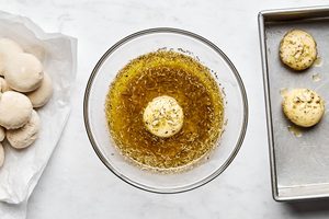 raw rhodes rolls being rolled in homemade garlic and herb butter