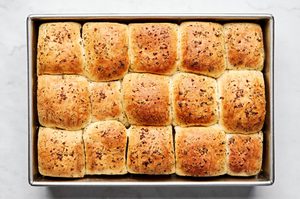 freshly baked dressed up rhodes rolls covered with melted herby butter and flaky salt