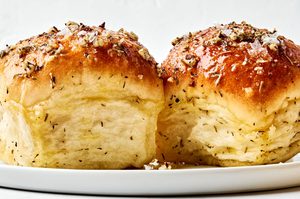 2 Freshly baked Rhodes rolls brushed with golden herby butter on a plate