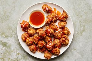 Crispy hot honey chicken nuggets drizzled with spicy sweet glaze on a plate, served with extra hot honey sauce for dipping