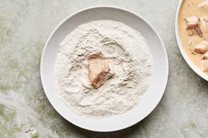 chicken breast pieces being dredged and breaded in egg, buttermilk and a flower mixture