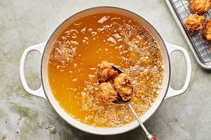 crispy breaded chicken nuggets frying in a deep pot of vegetable oil