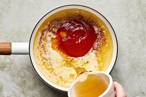 hot honey dipping sauce bieng made in a sauce pan with honey, sriracha and butter