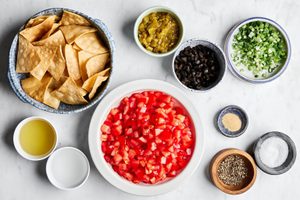 diced tomatoes, chiles, black olives, green onions, avocado oil, and spices in prep bowl to make tomato and olive salsa