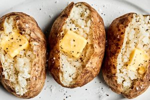 perfect baked potatoes cut open and topped with butter, salt and pepper