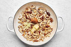 mushrooms and salt being cooked in a skillet with butter, miso paste, garlic and ginger to be served with pork chops