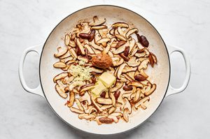 mushrooms and salt being cooked in a skillet with butter, miso paste, garlic and ginger to be served with pork chops