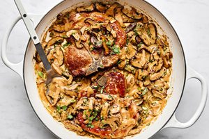Pork chops with miso mushrooms in a creamy sauce with cilantro and green onions in a skillet