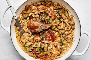 Pork chops with miso mushrooms in a creamy sauce with cilantro and green onions in a skillet