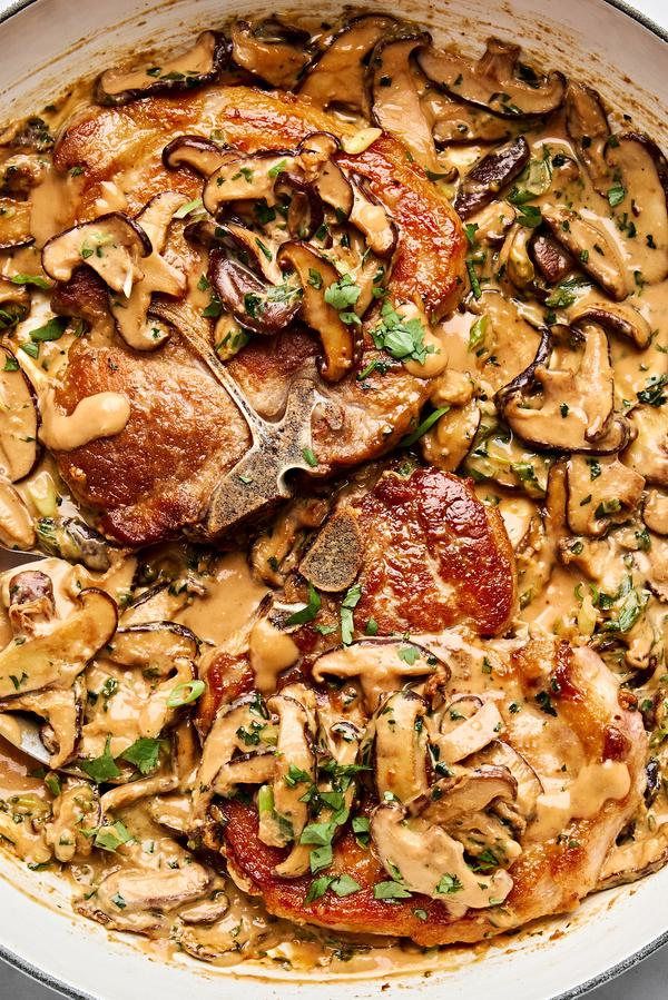 Pork chops with miso mushrooms in a creamy sauce with cilantro and green onions in a skillet
