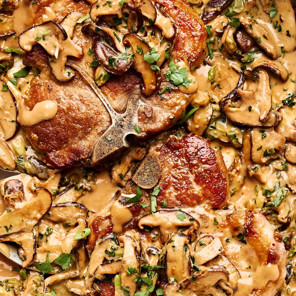 Pork chops with miso mushrooms in a creamy sauce with cilantro and green onions in a skillet