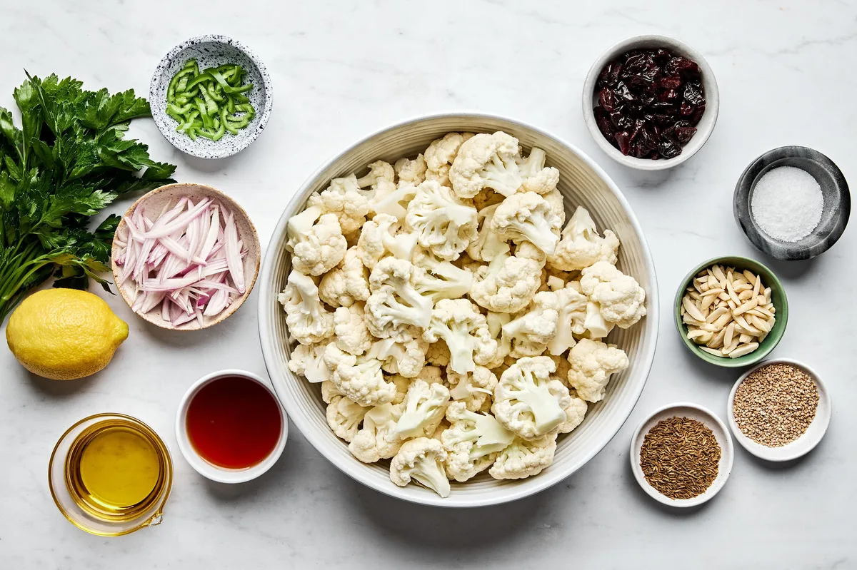 cauliflower, herbs, almonds, dried cherries, and spices in prep bowls to make roasted cauliflower salad