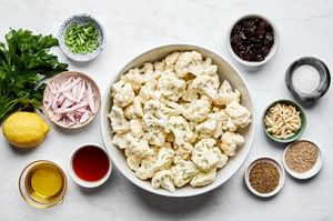 cauliflower, herbs, almonds, dried cherries, and spices in prep bowls to make roasted cauliflower salad