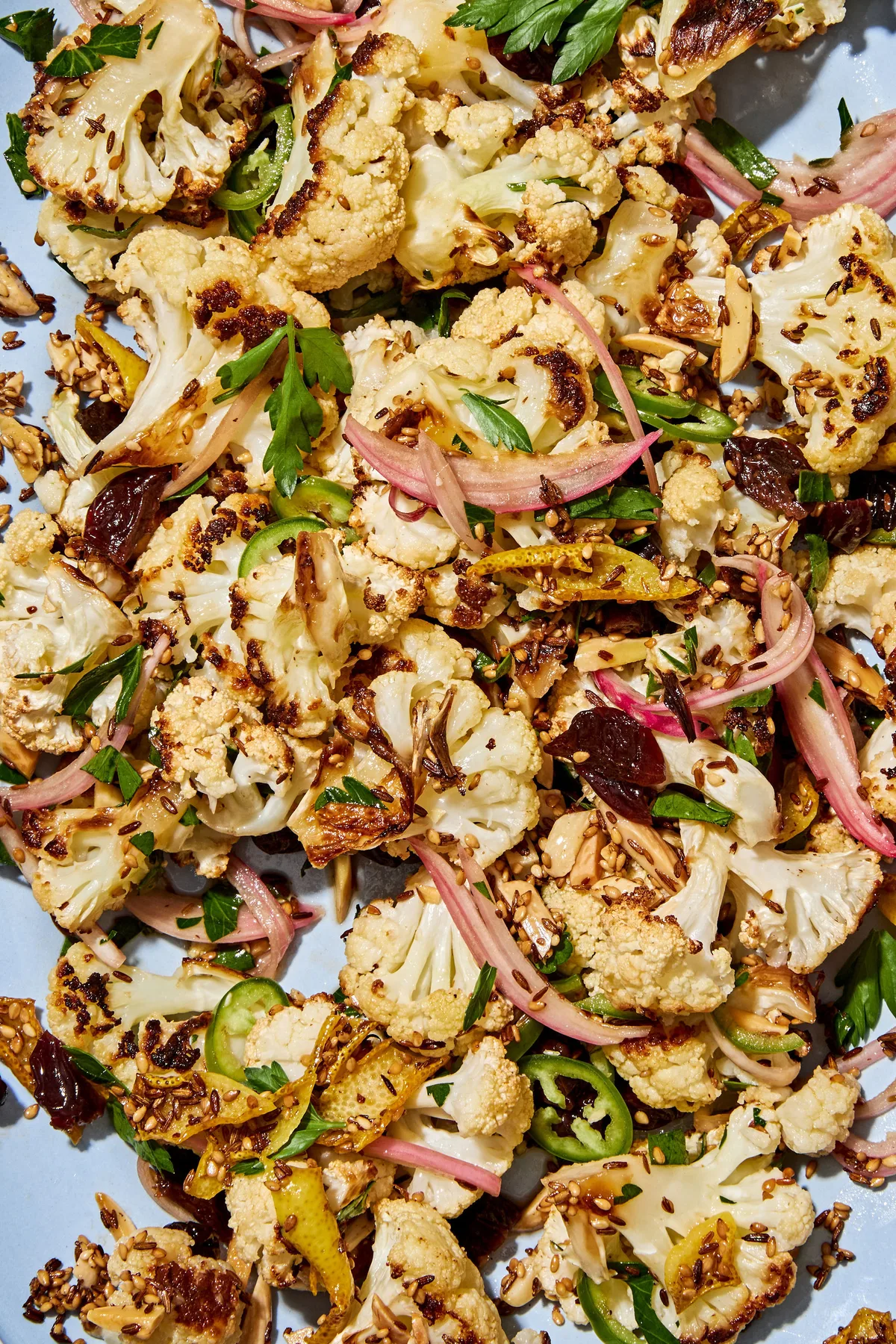 Roasted cauliflower salad with herbs, almonds, dried cherries, and spices on a serving plate.