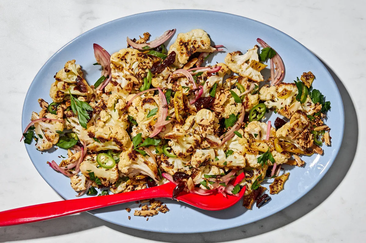 Roasted cauliflower salad with herbs, almonds, dried cherries, and spices on a serving plate.