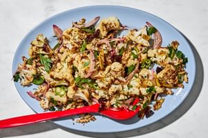 Roasted cauliflower salad with herbs, almonds, dried cherries, and spices on a serving plate.