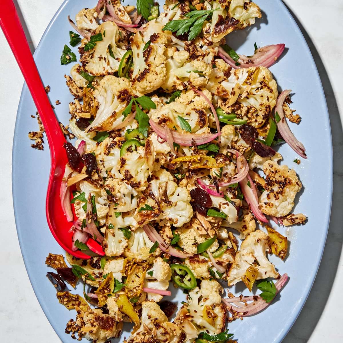 Roasted cauliflower salad with herbs, almonds, dried cherries, and spices on a serving plate.