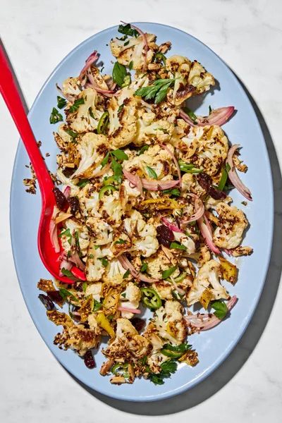 Roasted cauliflower salad with herbs, almonds, dried cherries, and spices on a serving plate.